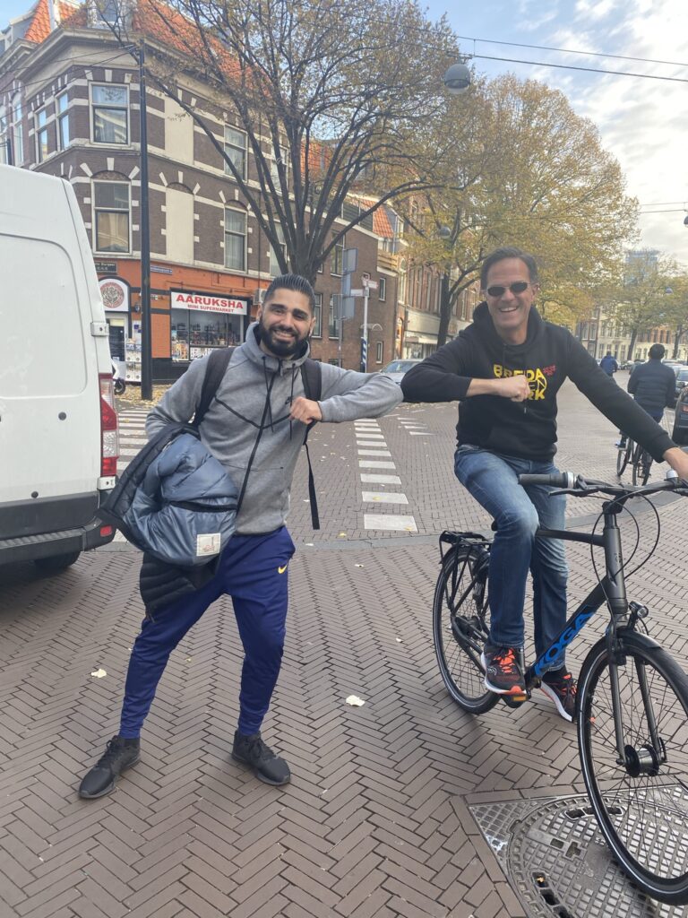 a man on a bike elbow bumping with a man holding a bag
